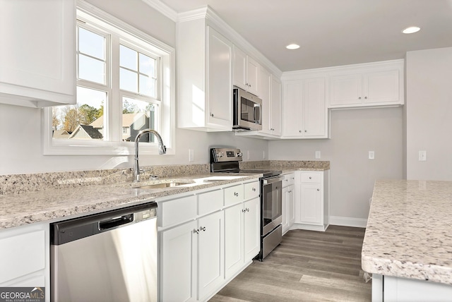 kitchen with recessed lighting, appliances with stainless steel finishes, light wood-style floors, white cabinets, and a sink