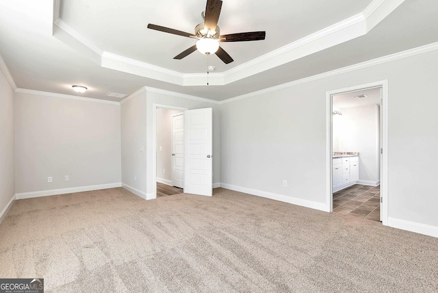 unfurnished bedroom with carpet floors, baseboards, a tray ceiling, and ornamental molding