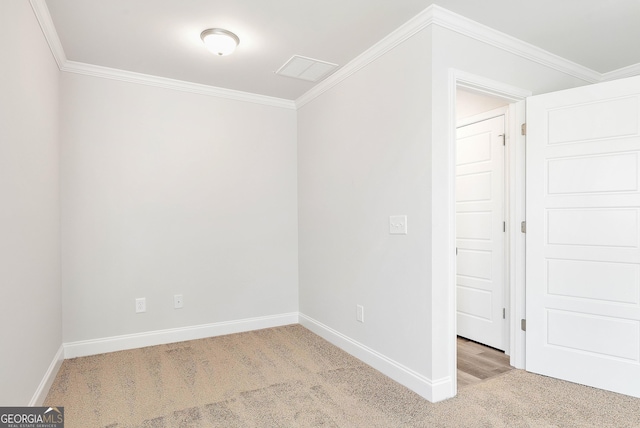 empty room with ornamental molding, light carpet, and baseboards