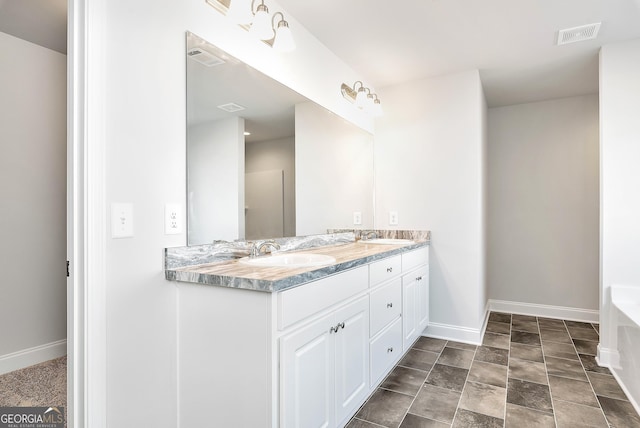 bathroom with visible vents, a sink, baseboards, and double vanity