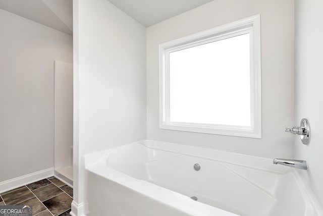 bathroom featuring a bath and baseboards