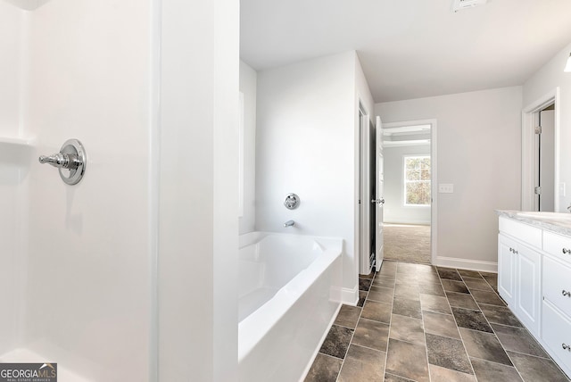 full bath with a garden tub, baseboards, and vanity