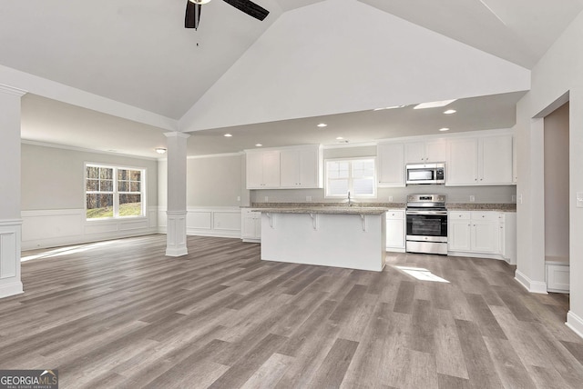 kitchen with a breakfast bar, ornate columns, white cabinets, and stainless steel appliances