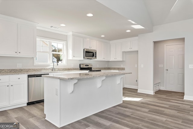 kitchen featuring stainless steel appliances, white cabinetry, and light wood-style floors