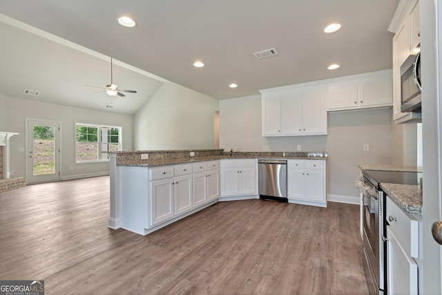 kitchen with a peninsula, appliances with stainless steel finishes, visible vents, and white cabinets