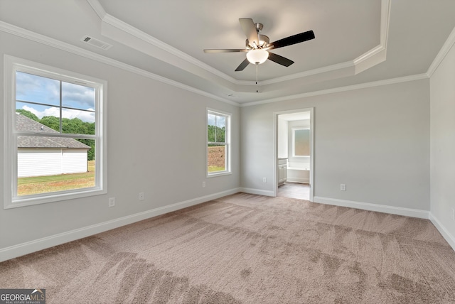 unfurnished bedroom featuring ornamental molding, a tray ceiling, light colored carpet, and visible vents