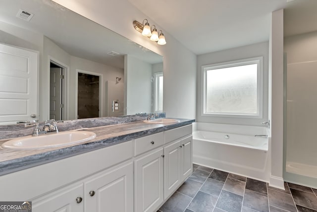 bathroom featuring double vanity, visible vents, a sink, and a bath