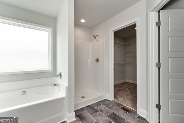 full bath with a garden tub, recessed lighting, a spacious closet, a shower stall, and baseboards