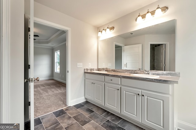 bathroom with double vanity, ornamental molding, a sink, and baseboards