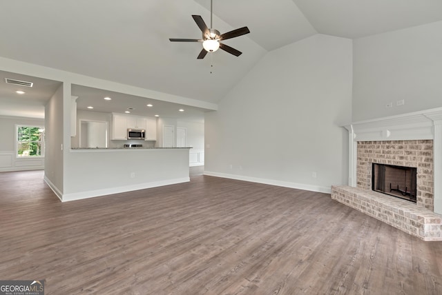 unfurnished living room with a ceiling fan, visible vents, a fireplace, and wood finished floors