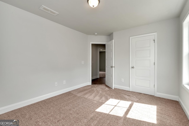 unfurnished bedroom featuring carpet floors, visible vents, and baseboards