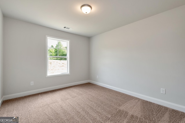 spare room with carpet flooring, visible vents, and baseboards