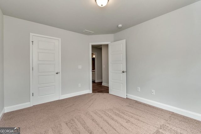 unfurnished bedroom with carpet floors, visible vents, and baseboards