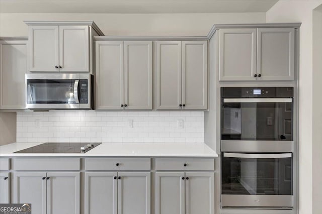 kitchen with light countertops, appliances with stainless steel finishes, gray cabinets, and tasteful backsplash