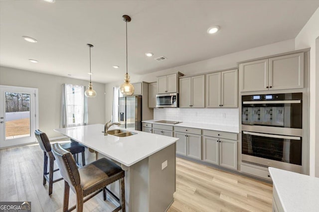 kitchen with appliances with stainless steel finishes, backsplash, gray cabinets, and visible vents