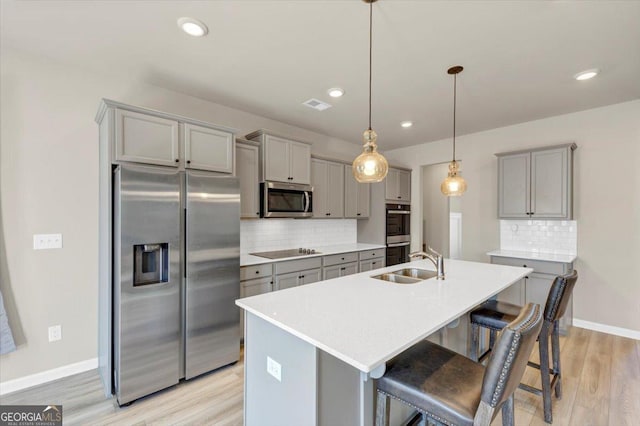 kitchen featuring stainless steel appliances, light wood-style floors, gray cabinets, and a sink