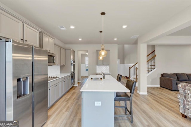 kitchen with visible vents, a breakfast bar area, appliances with stainless steel finishes, gray cabinets, and a sink