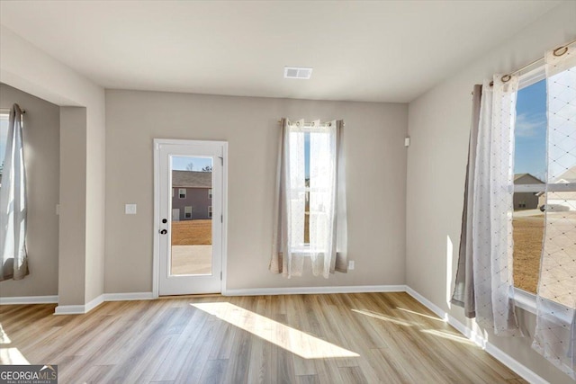 doorway with wood finished floors, visible vents, and baseboards