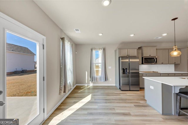 kitchen featuring light wood finished floors, visible vents, decorative backsplash, stainless steel appliances, and light countertops