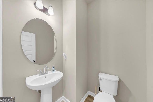 bathroom featuring baseboards, a sink, and toilet