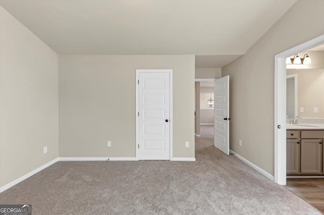 unfurnished bedroom with carpet flooring, a sink, baseboards, and ensuite bathroom