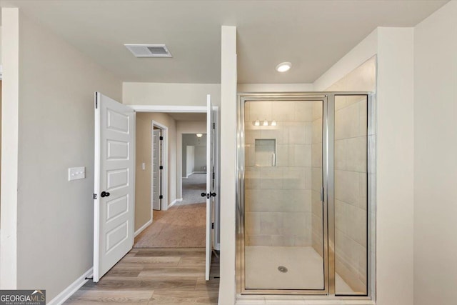 full bathroom with visible vents, a shower stall, baseboards, and wood finished floors