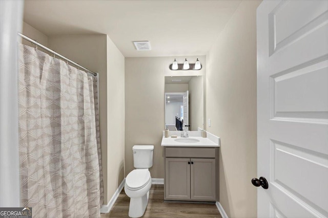 full bathroom with baseboards, visible vents, toilet, wood finished floors, and vanity