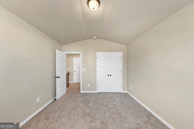 unfurnished bedroom with vaulted ceiling, carpet floors, a closet, and baseboards