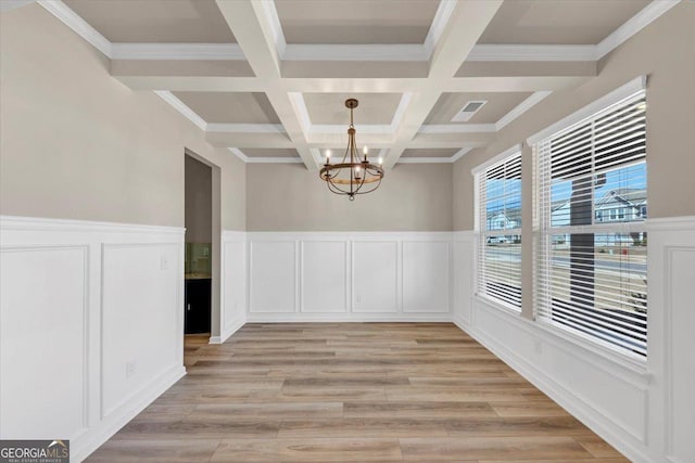 unfurnished dining area featuring light wood finished floors, coffered ceiling, beamed ceiling, and an inviting chandelier