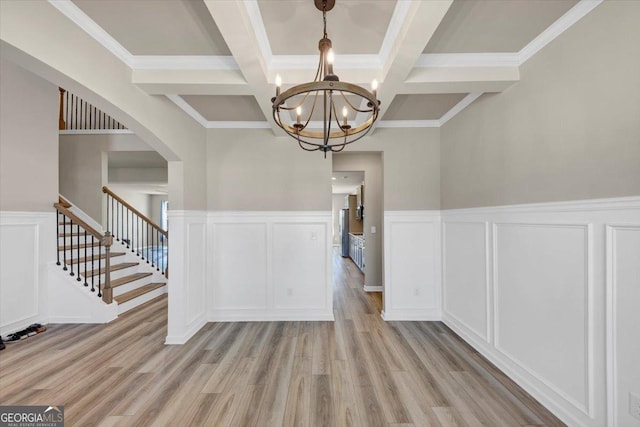 unfurnished dining area with a notable chandelier, beamed ceiling, and light wood-style flooring