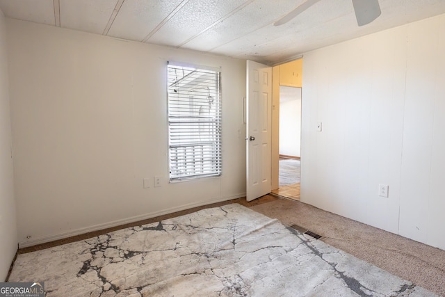 carpeted empty room featuring visible vents and ceiling fan