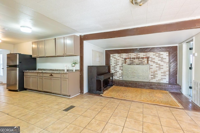 kitchen with light tile patterned floors, visible vents, a brick fireplace, gray cabinets, and freestanding refrigerator