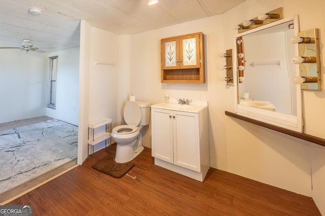 bathroom featuring toilet, wood finished floors, vanity, and a ceiling fan