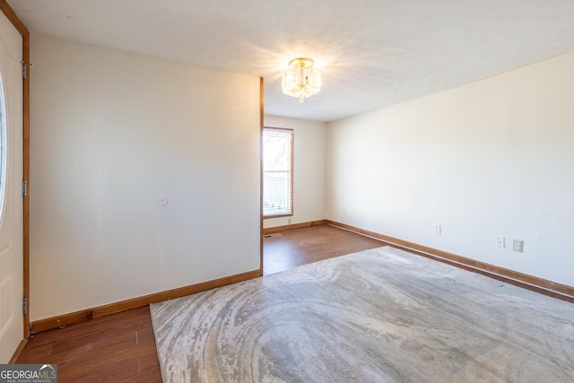 unfurnished bedroom with an inviting chandelier, baseboards, and wood finished floors