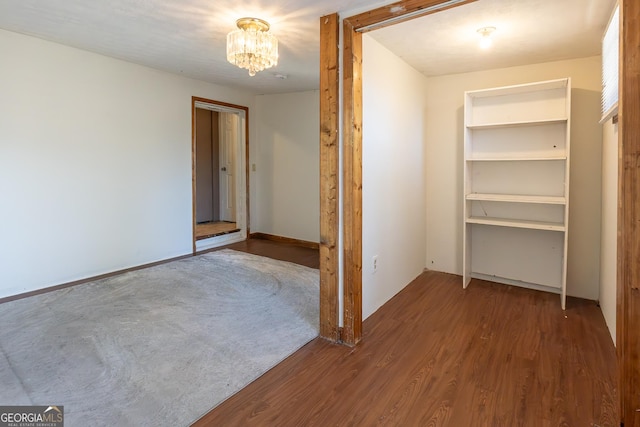 unfurnished bedroom with wood finished floors and a notable chandelier