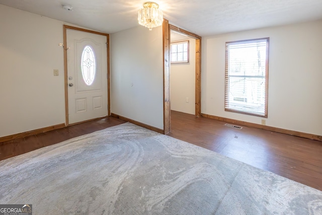 entryway featuring baseboards, visible vents, an inviting chandelier, and wood finished floors