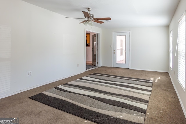 carpeted spare room featuring baseboards and ceiling fan