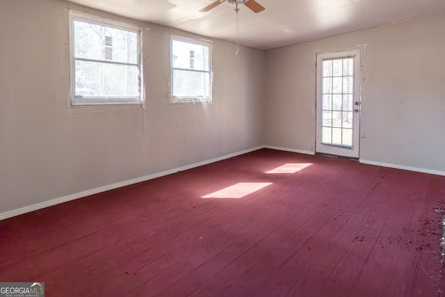 unfurnished room featuring baseboards, a wealth of natural light, a ceiling fan, and hardwood / wood-style flooring