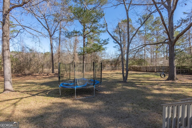 view of yard featuring a trampoline and fence