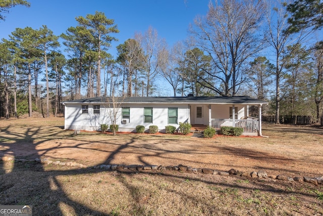 ranch-style house featuring covered porch and a front lawn