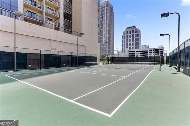 view of sport court featuring a view of city and fence