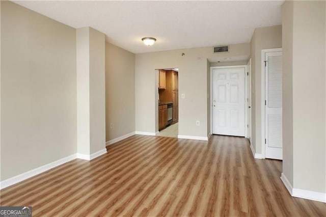 unfurnished room with light wood-style flooring, visible vents, and baseboards