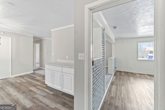 hallway featuring a textured ceiling, baseboards, and wood finished floors