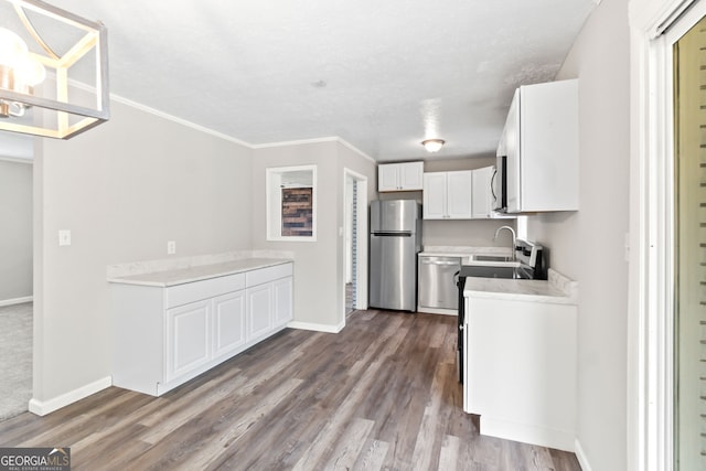 kitchen featuring appliances with stainless steel finishes, white cabinets, light countertops, and wood finished floors