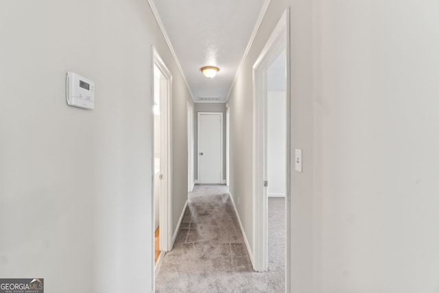 hallway with light carpet, crown molding, visible vents, and baseboards