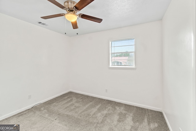 carpeted spare room with baseboards, visible vents, and a ceiling fan