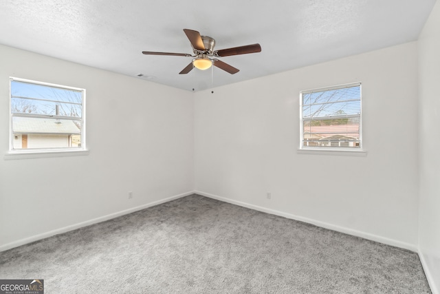 spare room featuring a textured ceiling, a ceiling fan, visible vents, baseboards, and carpet