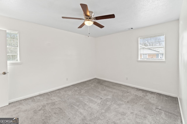 empty room with a wealth of natural light, baseboards, visible vents, and carpet flooring