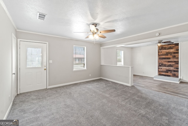 interior space featuring visible vents, ceiling fan, ornamental molding, a textured ceiling, and carpet floors