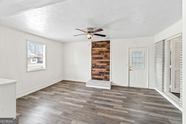 unfurnished living room with a textured ceiling, ceiling fan, wood finished floors, and baseboards